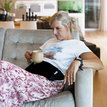 Load image into Gallery viewer, older woman relaxing on couch drinking tea wearing the hottle heat pack on stomach
