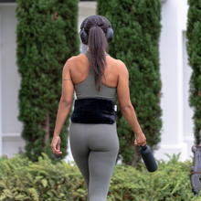 Load image into Gallery viewer, girl on a walk with the hottle heat pack and clay insert on her back for back pain
